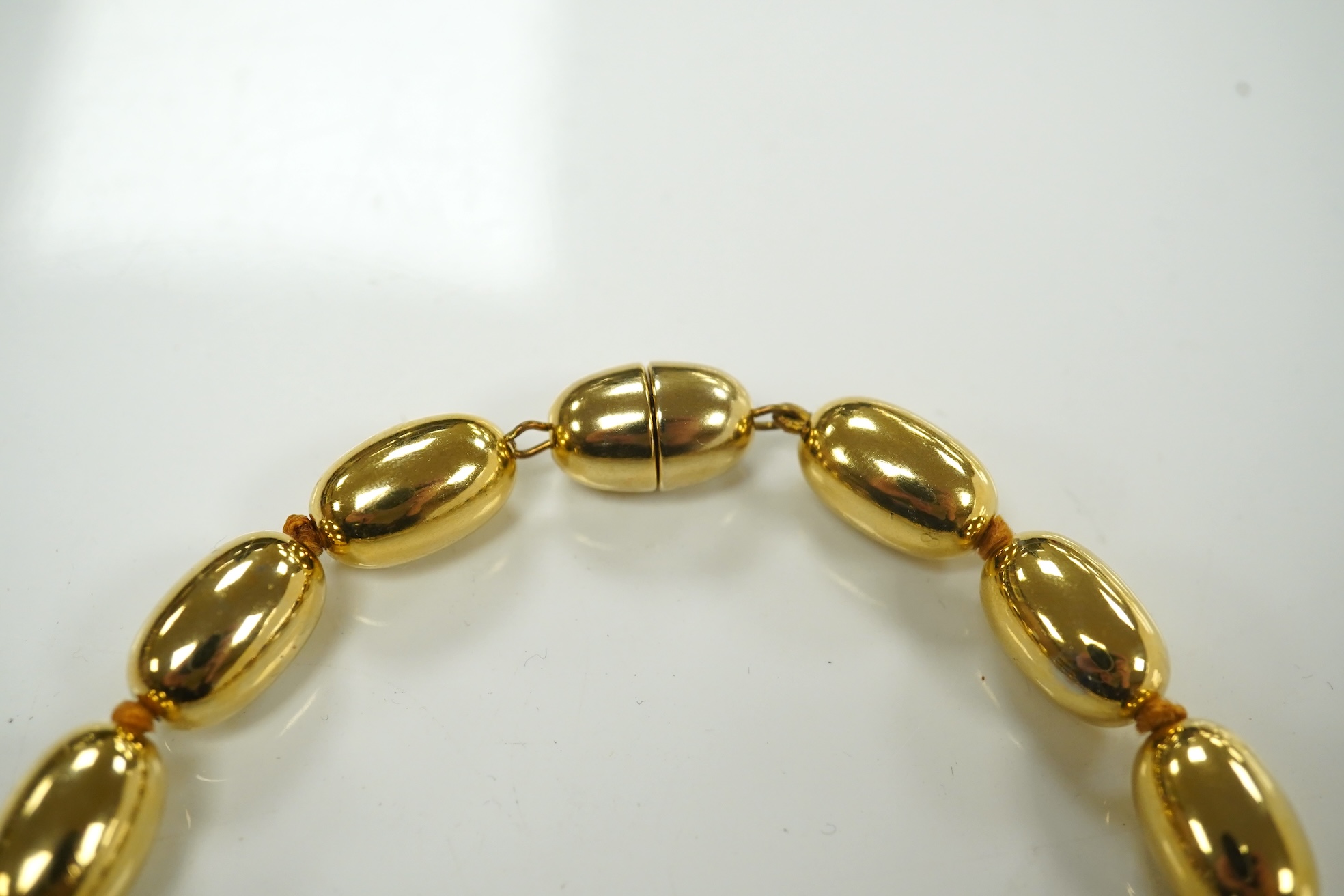 A modern gilt metal graduated oval bead costume necklace, 72cm. Condition - fair to good